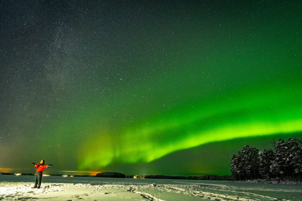 Aurora Borealis illuminates the night sky over a snowy landscape in Rovaniemi, Finland.