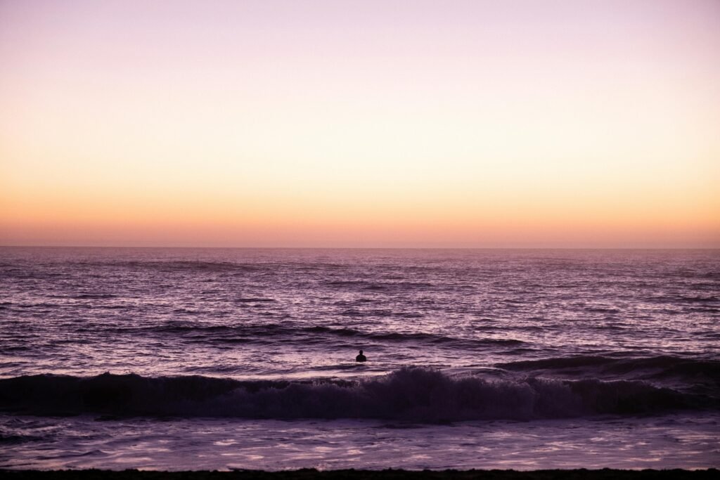 Silhouetted person watching a stunning sunset over the Atlantic Ocean in Hossegor, France.