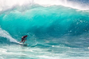 Thrilling surfing on massive turquoise waves, capturing the essence of ocean sports and adventure.