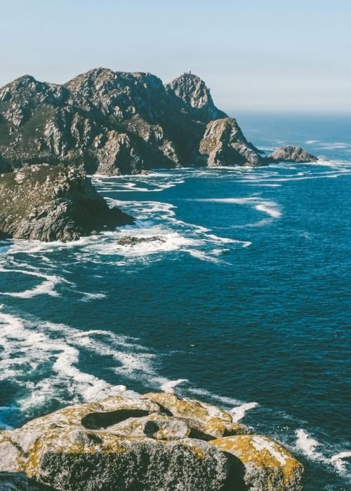 pexels-photo-584928-584928 Breathtaking view of the rocky coastline in Galicia, Spain with waves crashing against the cliffs under a clear blue sky.